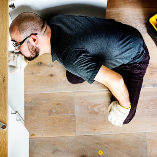 Man fixing kitchen sink - image by © rawpixel