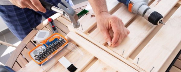 Hands driving nail with hammer into wooden shelf - www.freepik.com