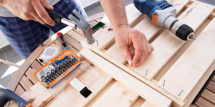 Hands driving nail with hammer into wooden shelf - www.freepik.com